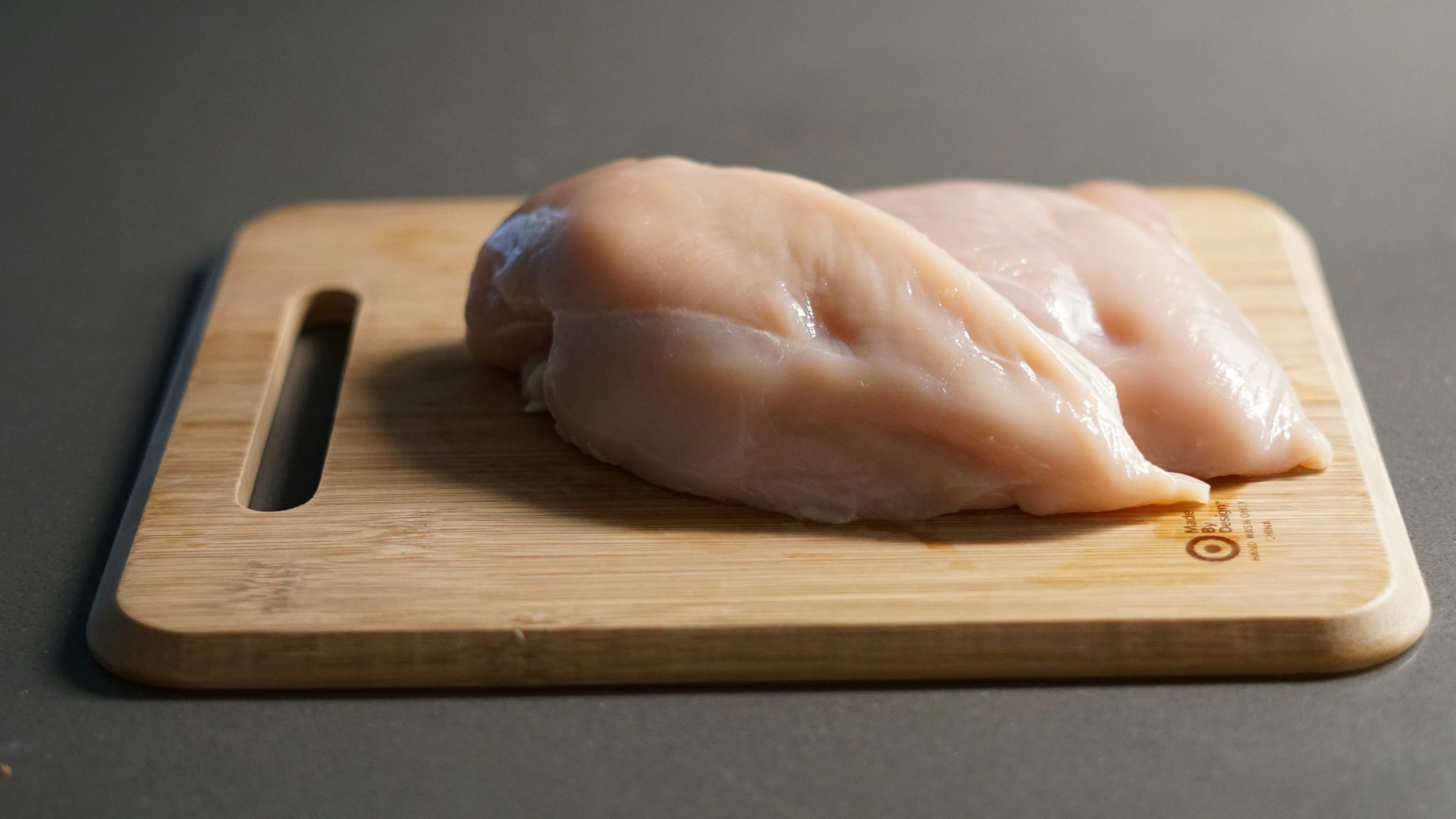 Raw chicken on a chpping board.