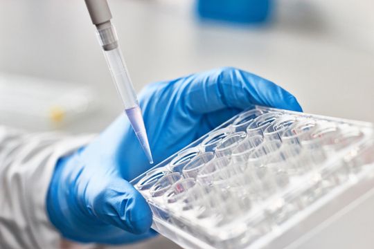 A closeup of a scientist holding a pipette.